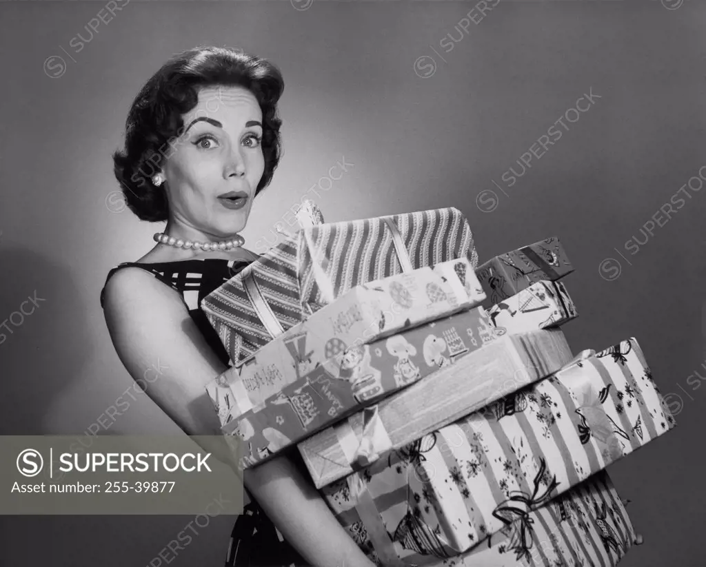 Portrait of a young woman holding a stack of Christmas present