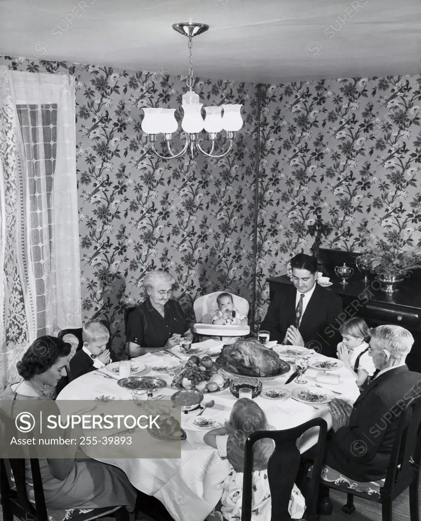 High angle view of a family praying at a dining table on Thanksgiving Day