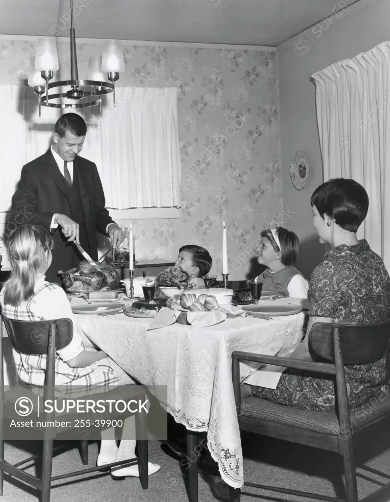 Mature couple sitting at a dining table with their children on Thanksgiving Day