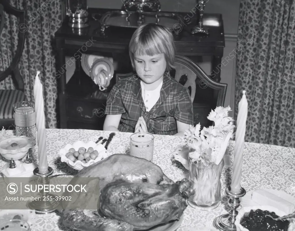 High angle view of a girl sitting at a dining table and looking at a roasted turkey on Thanksgiving Day