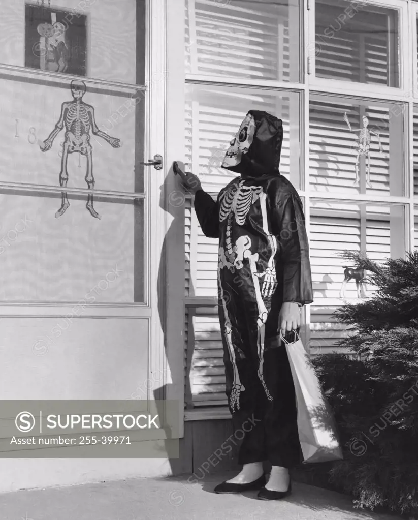 Person wearing a Halloween costume pressing the doorbell of a house