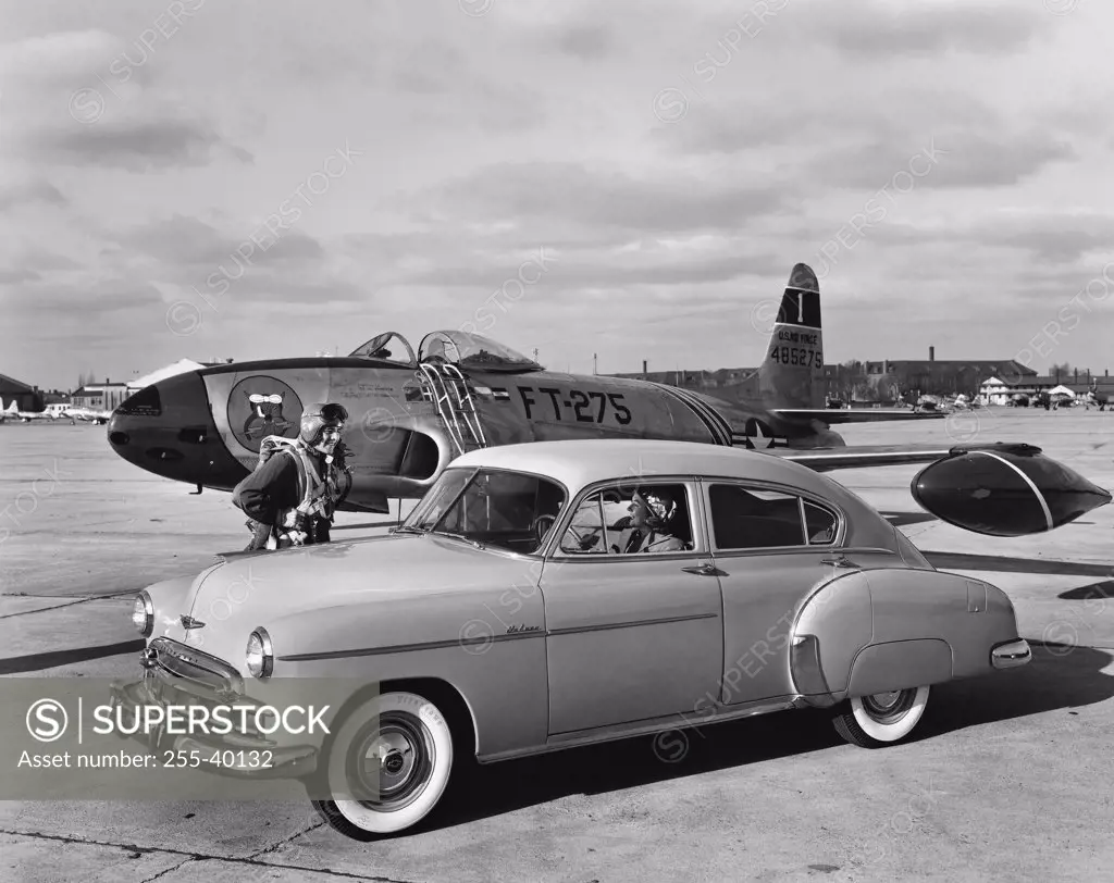 Vintage car near an airplane on a runway