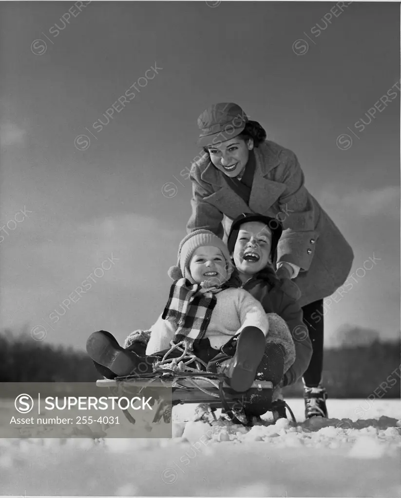 Mother pushing her children on a sled