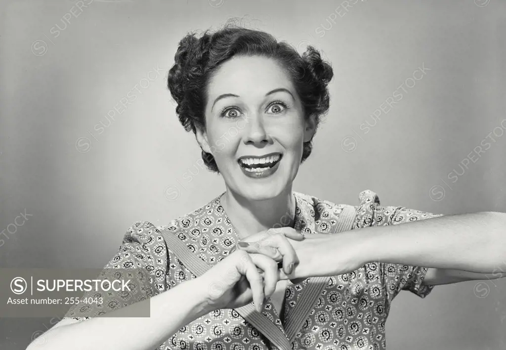 Vintage photograph. Brunette woman smiling with wide eyes holding hands up with fingers clasped