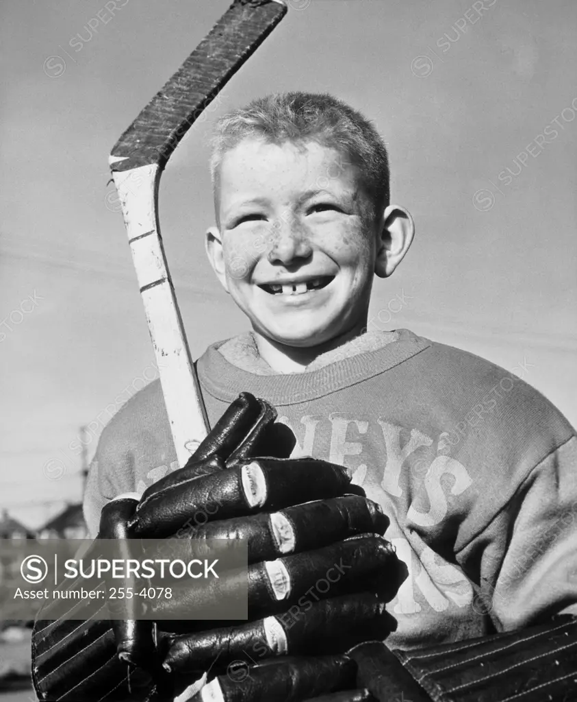 Close-up of a boy holding a hockey stick smiling