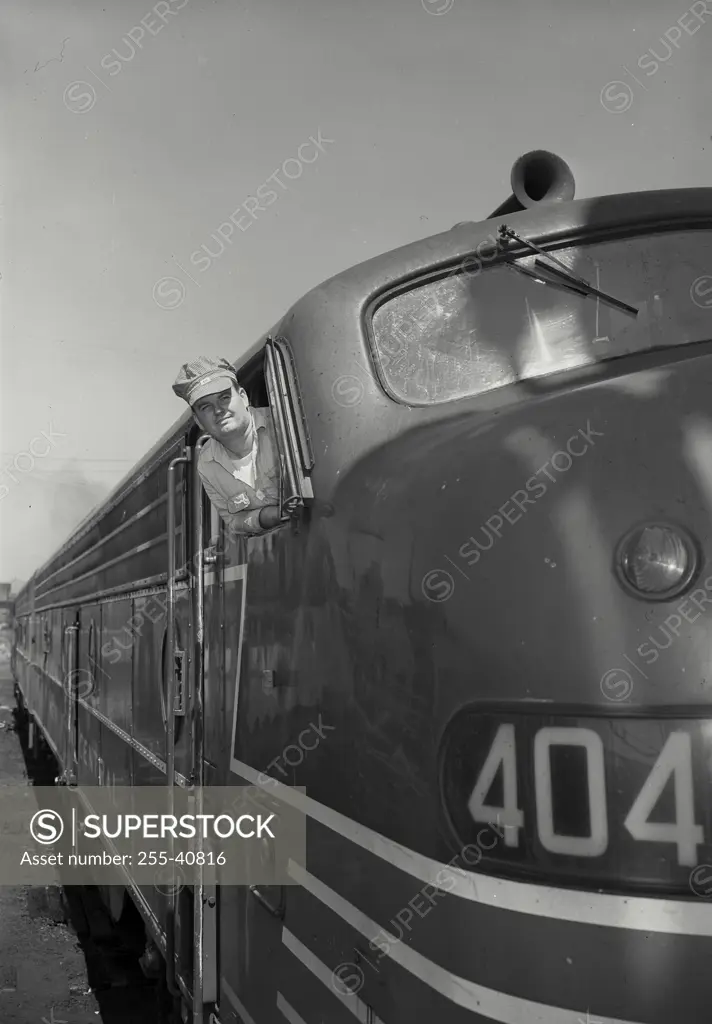 Vintage Photograph. Railroad engineer leaning out of cab window smiling and looking straight ahead