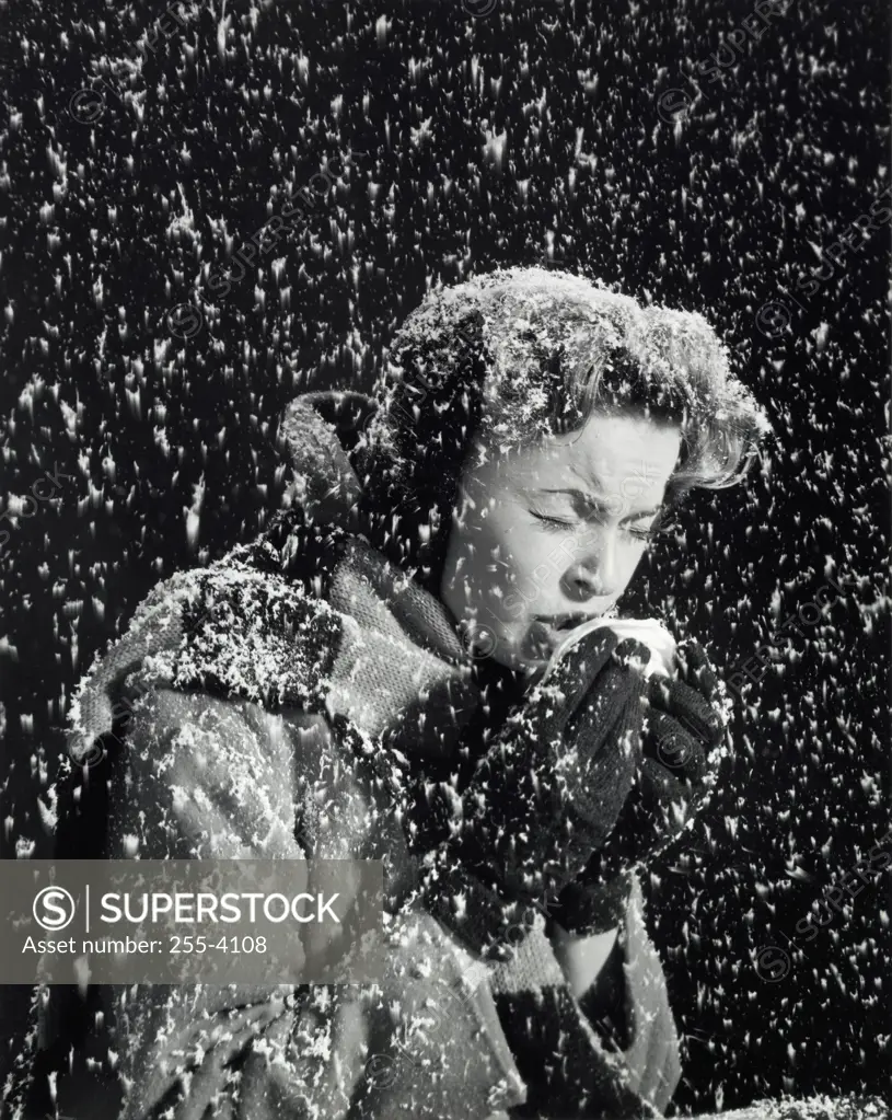 Side profile of a young woman sneezing in a snow fall