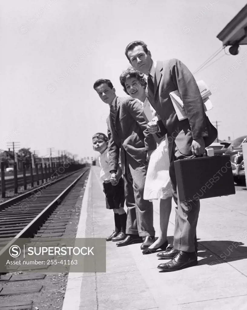 Parents with their children standing on a railroad station platform