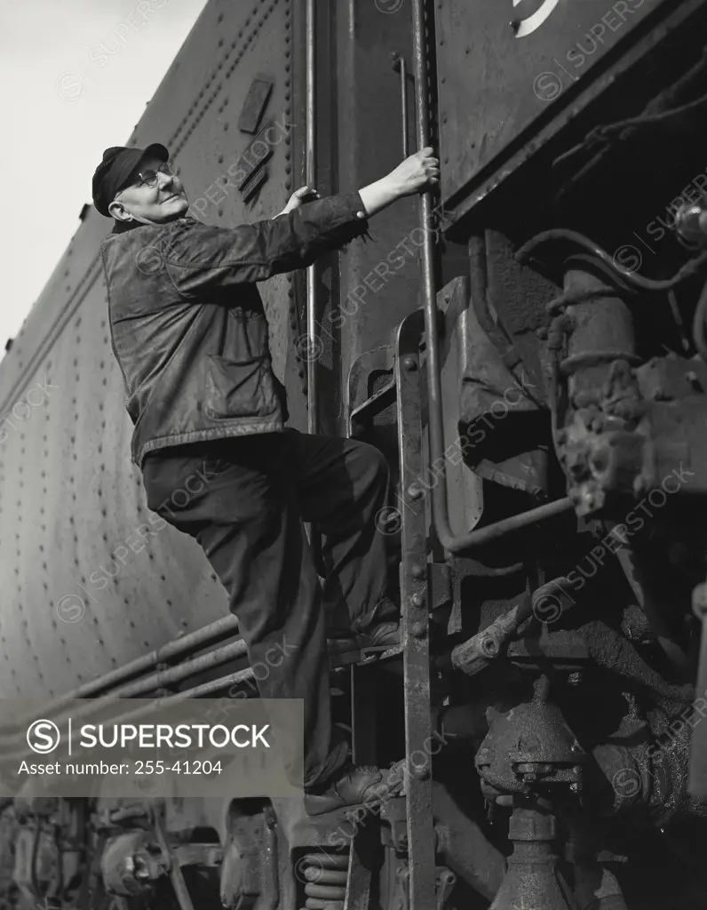 Vintage photograph. Railroad engineer climbing into locomotive