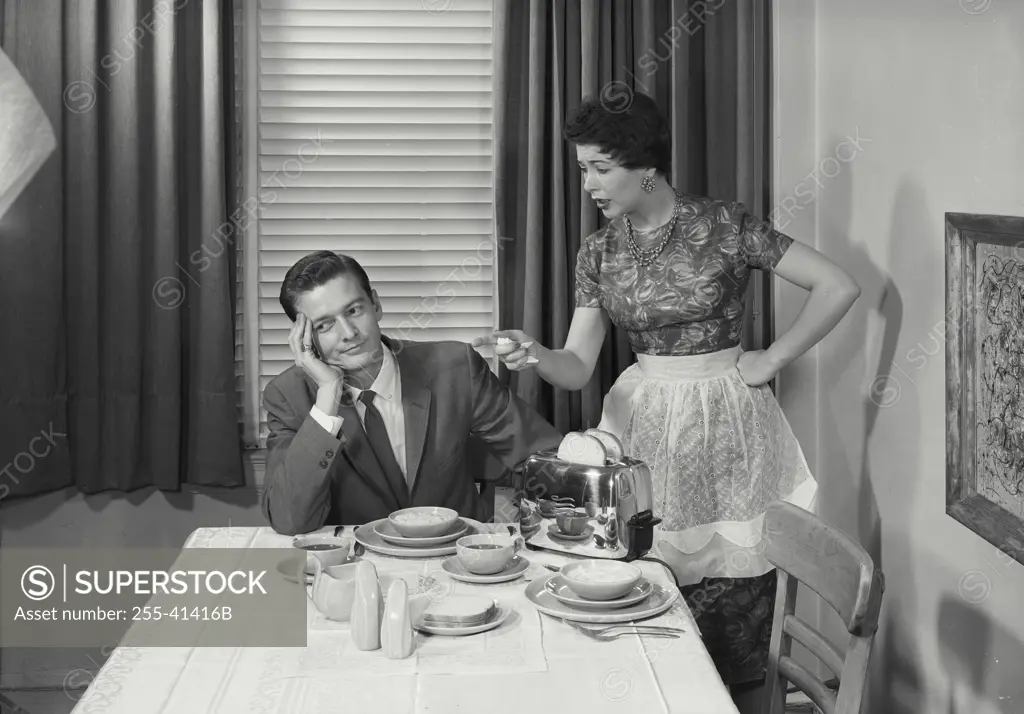 Vintage Photograph. Wife scolding husband in dining room.