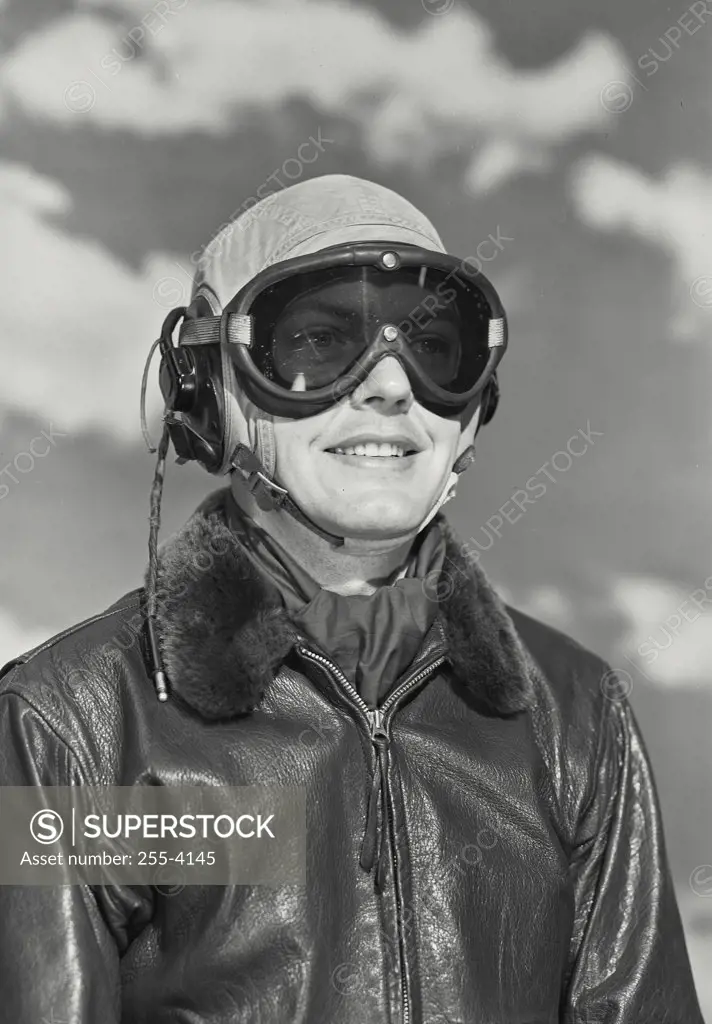 Vintage photograph. Man in pilots head gear and bomber jacket smiling off camera