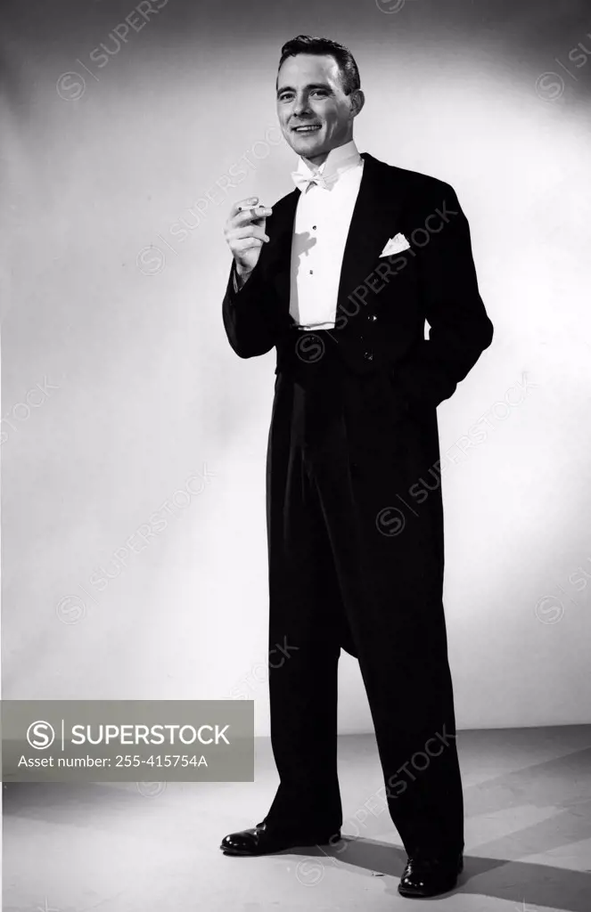 Elegant young man holding cigarette, studio shot