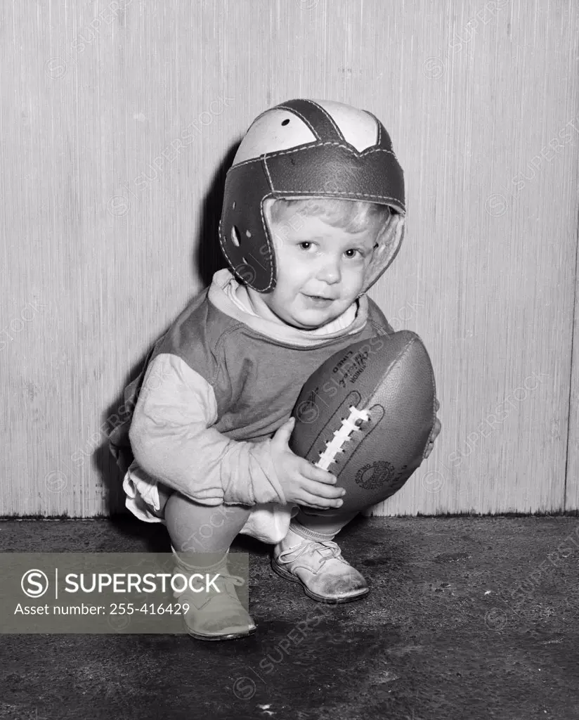 Portrait of small boy wearing baseball helmet and holding baseball ball