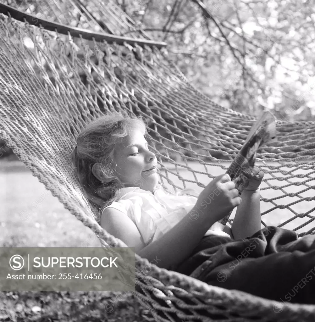 Woman reading newspaper in hammock