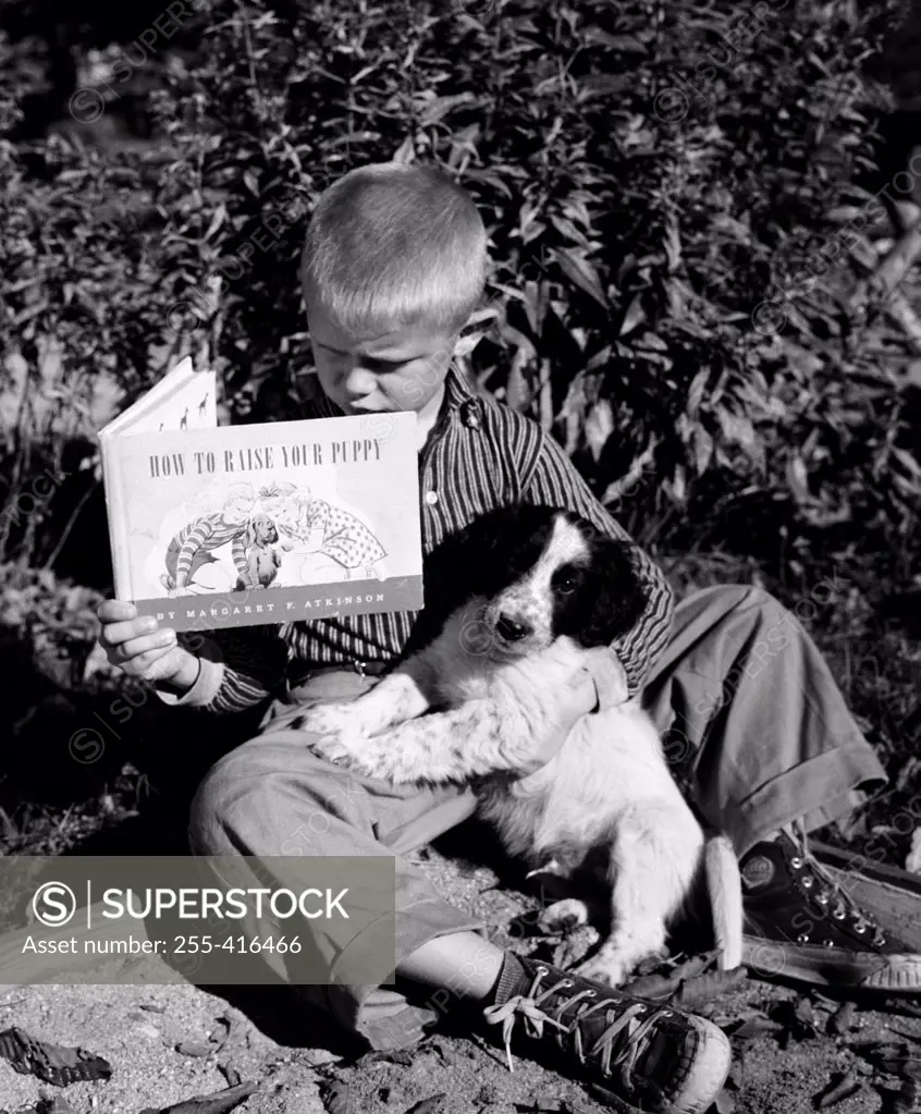 Boy sitting with dog and reading book