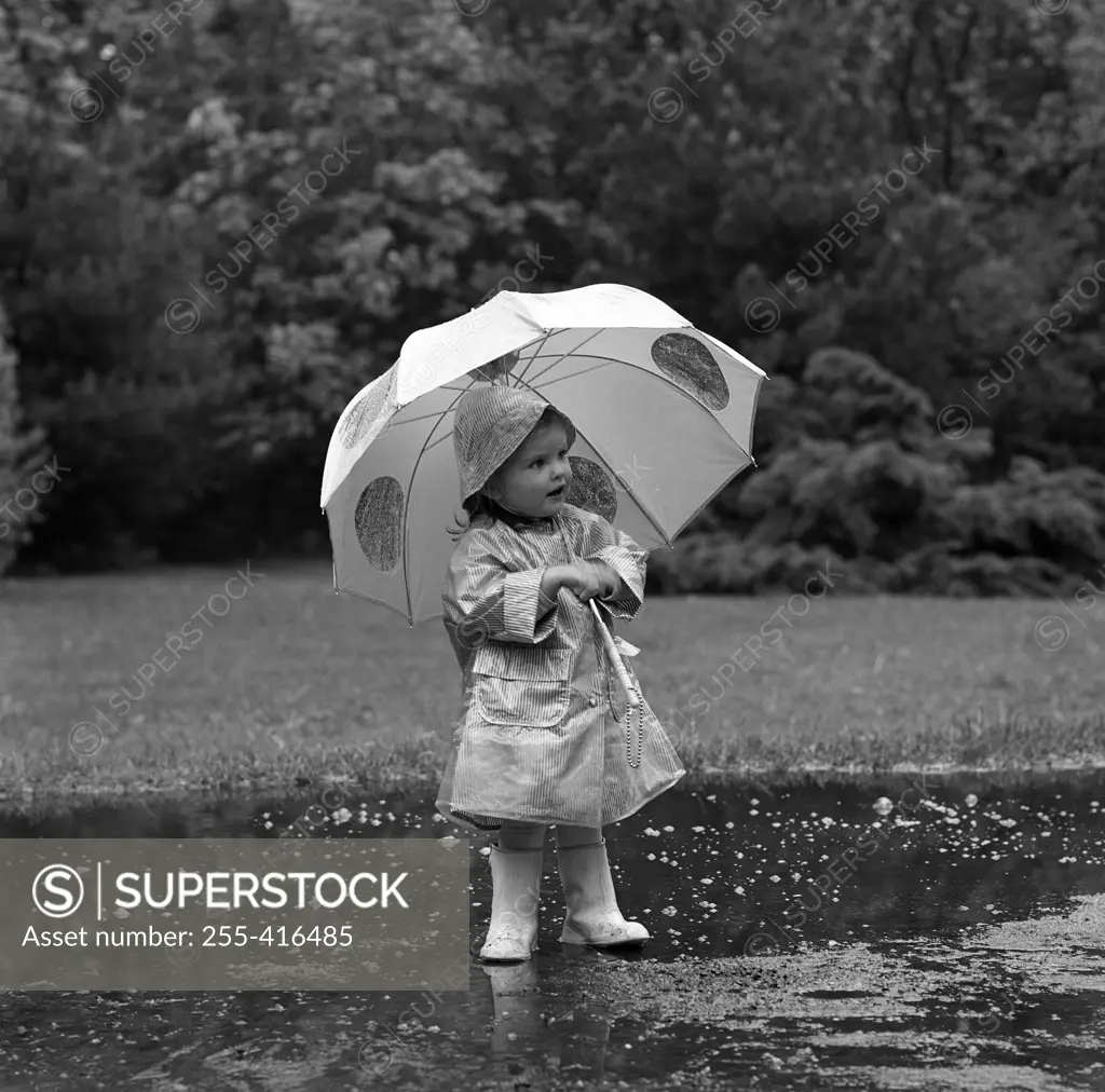 Small girl walking in rain with umbrella