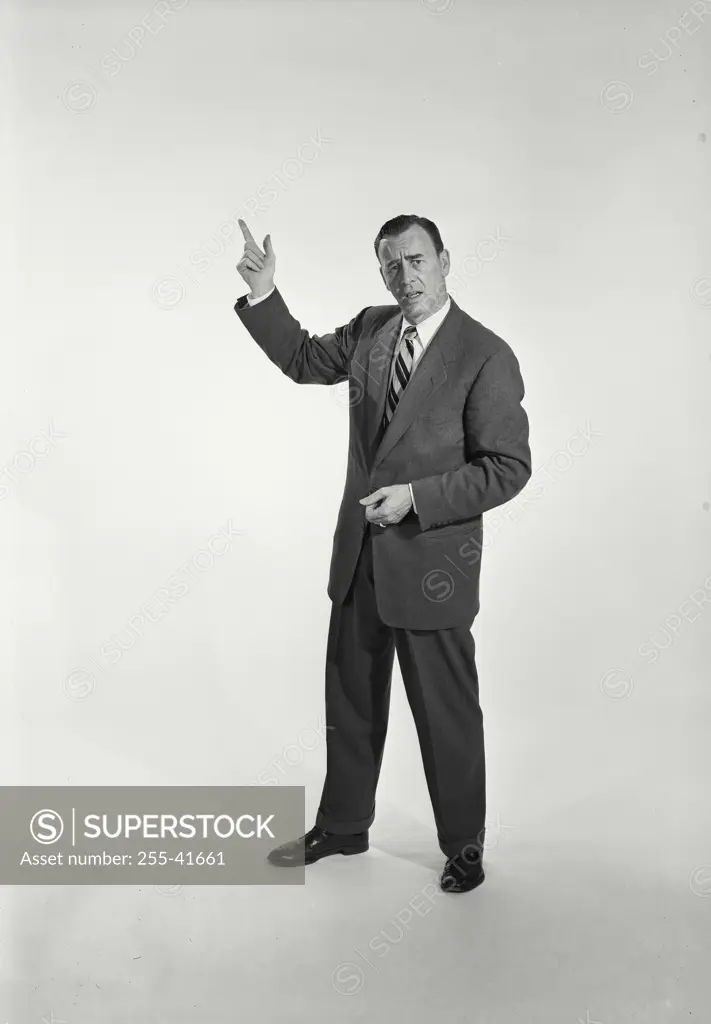 Vintage Photograph. Man in suit and tie standing on white background making finger gun. Frame 2