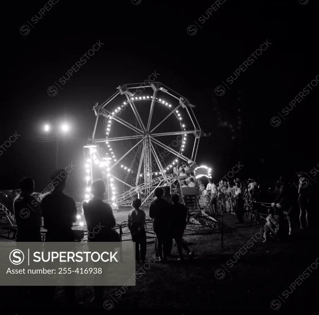 People in amusement park at night