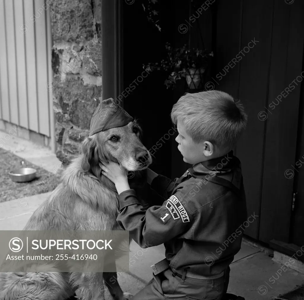 Boy scout in uniform with dog wearing scout hat