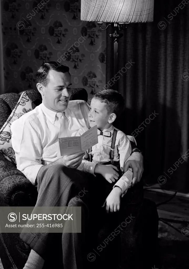 Pride father sitting with son and holding report card