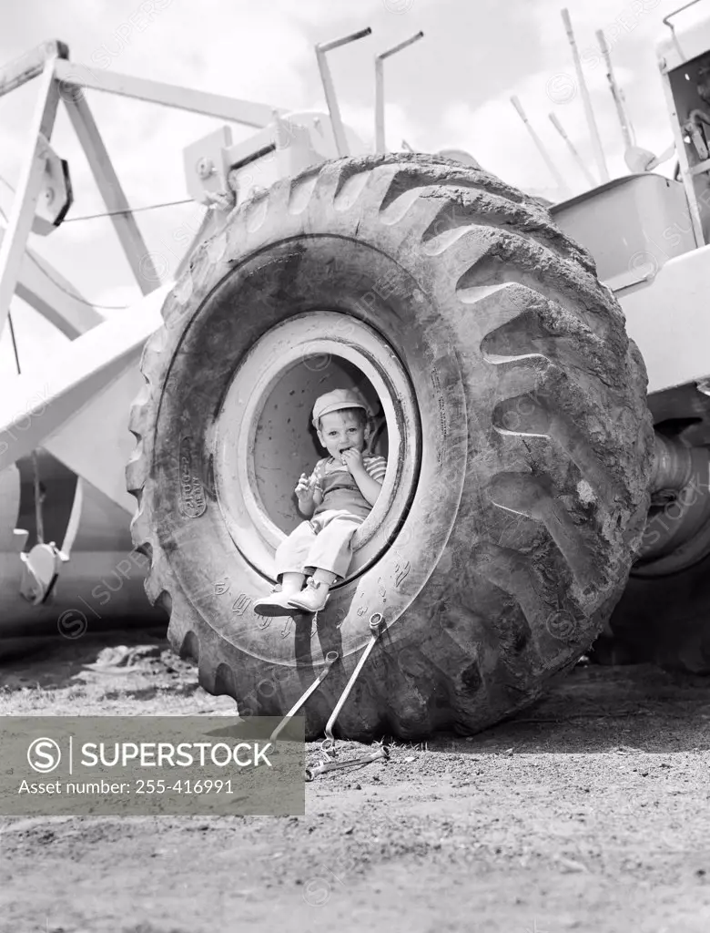 Boy sitting in vehicle's tire