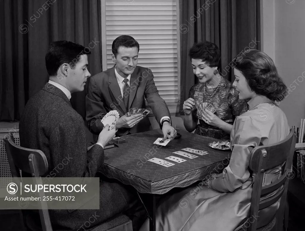 Two couples playing cards indoors
