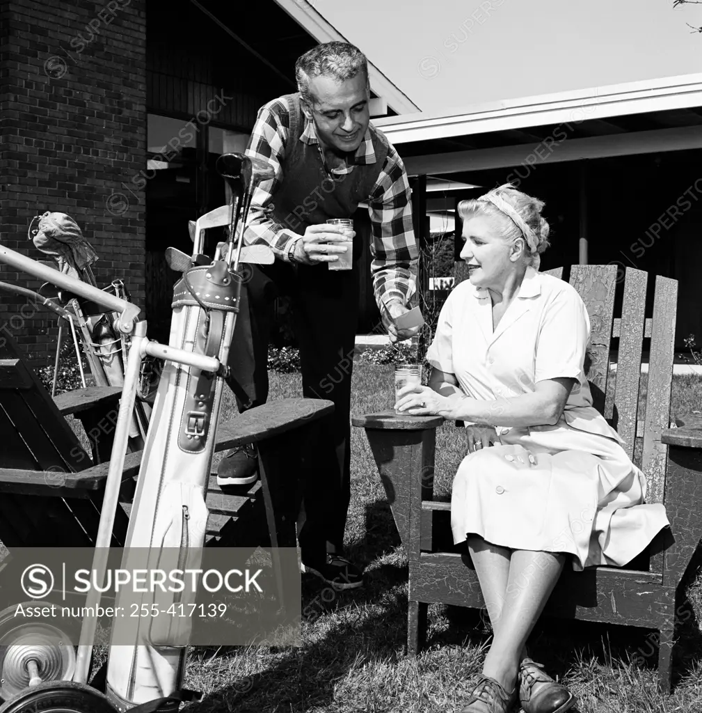 Mid adult man and mother having break from playing golf