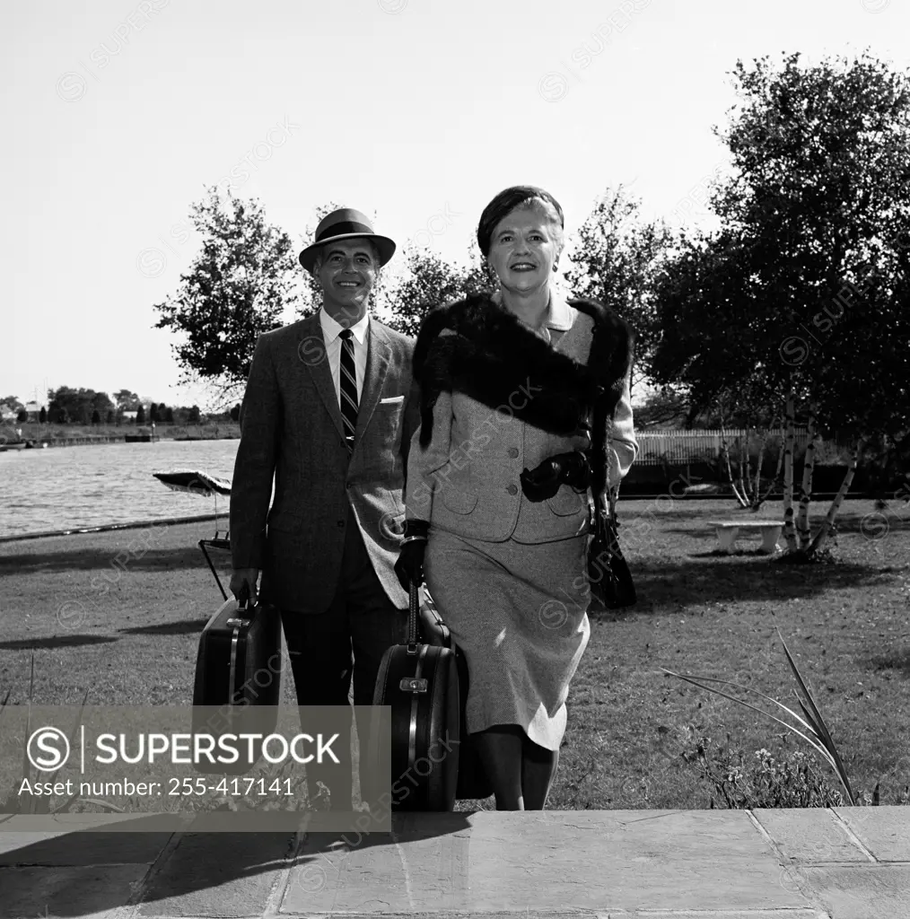 Mature couple carrying suitcases, walking up stairs