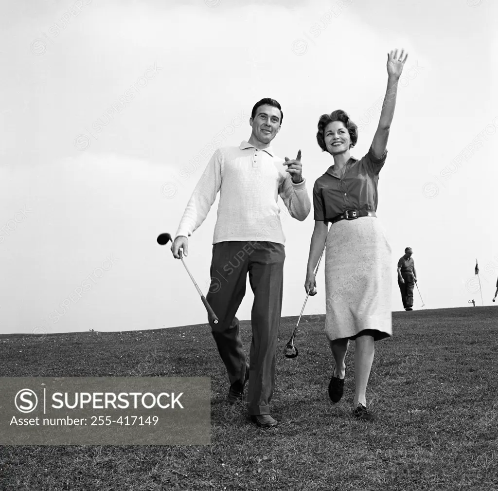 Mid adult man and mid-adult woman walking in golf course