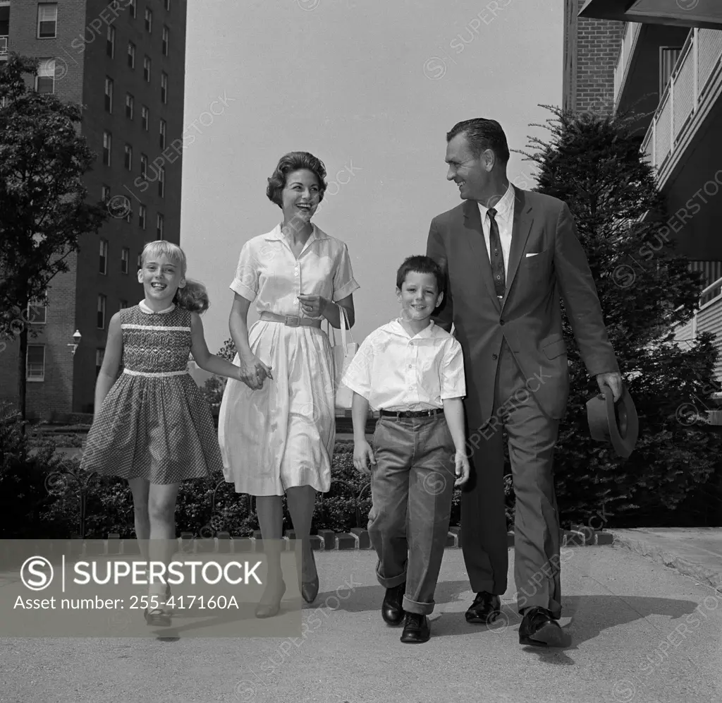 Boy and girl walking with parents outside flats