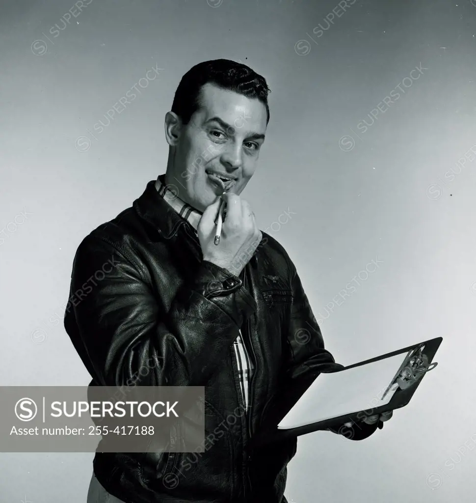 Studio portrait of man holding clipboard and pen