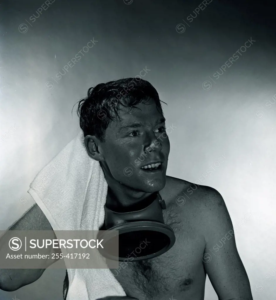 Studio shot of man with gas mask drying hair with towel