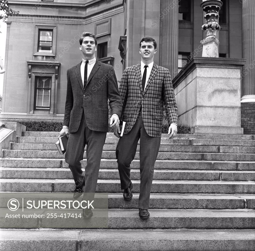 Two well dressed young men going down on stairs