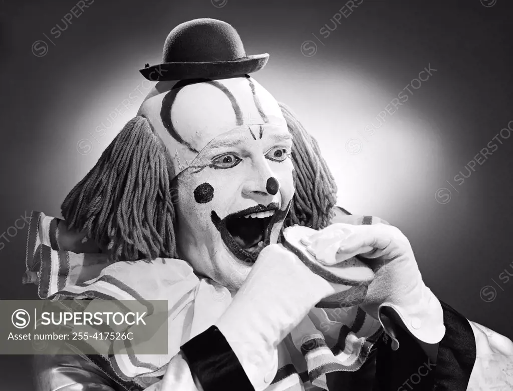 Studio shot of clown eating sandwich