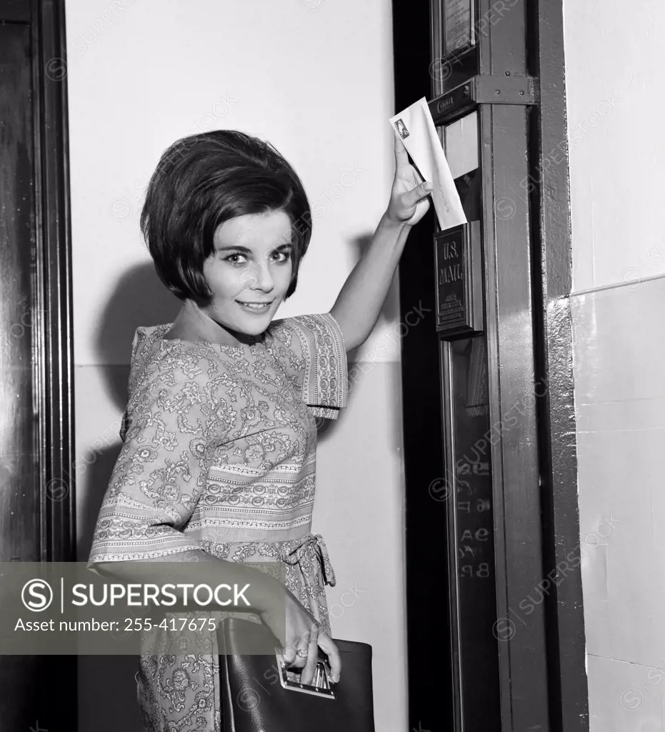 Young woman putting letter in letter box