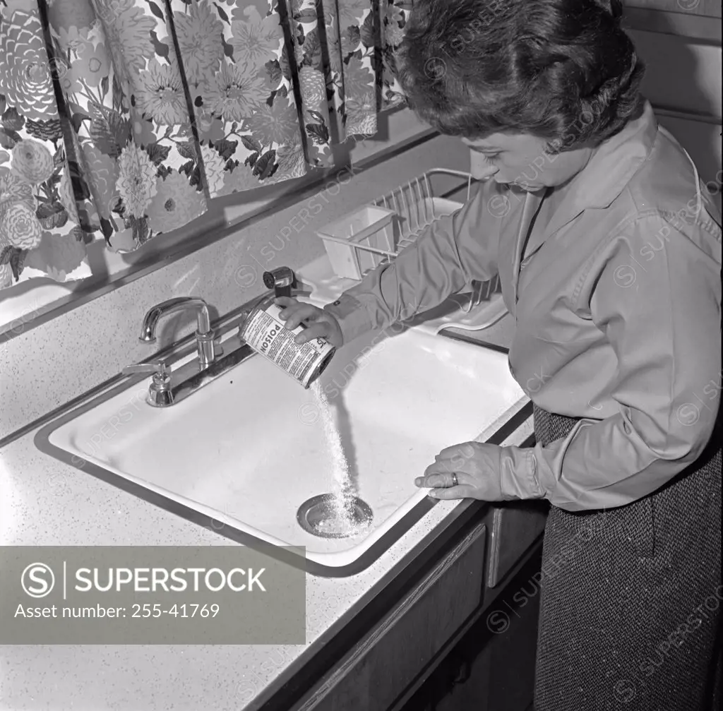High angle view of a young woman pouring drain cleaner into a sink