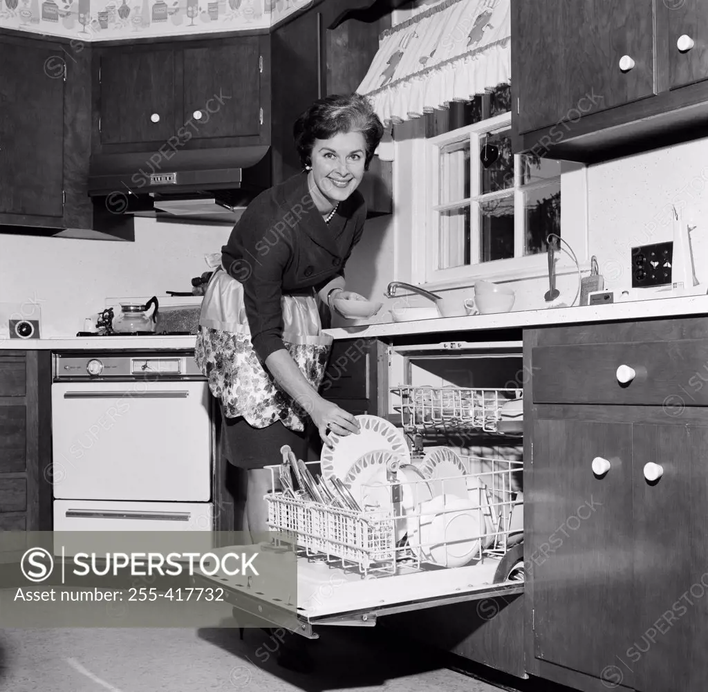 Mature housewife washing dishes in dishwasher
