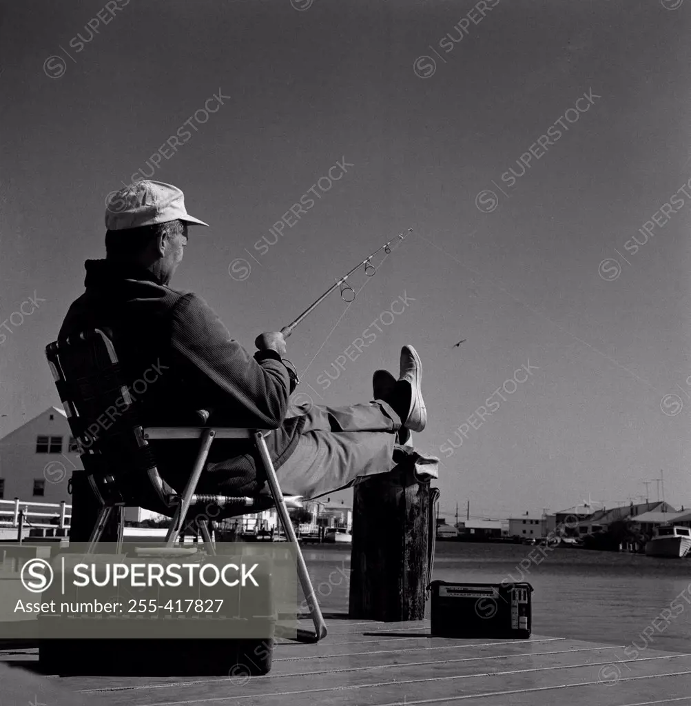 Fisherman sitting in chair at the edge of water