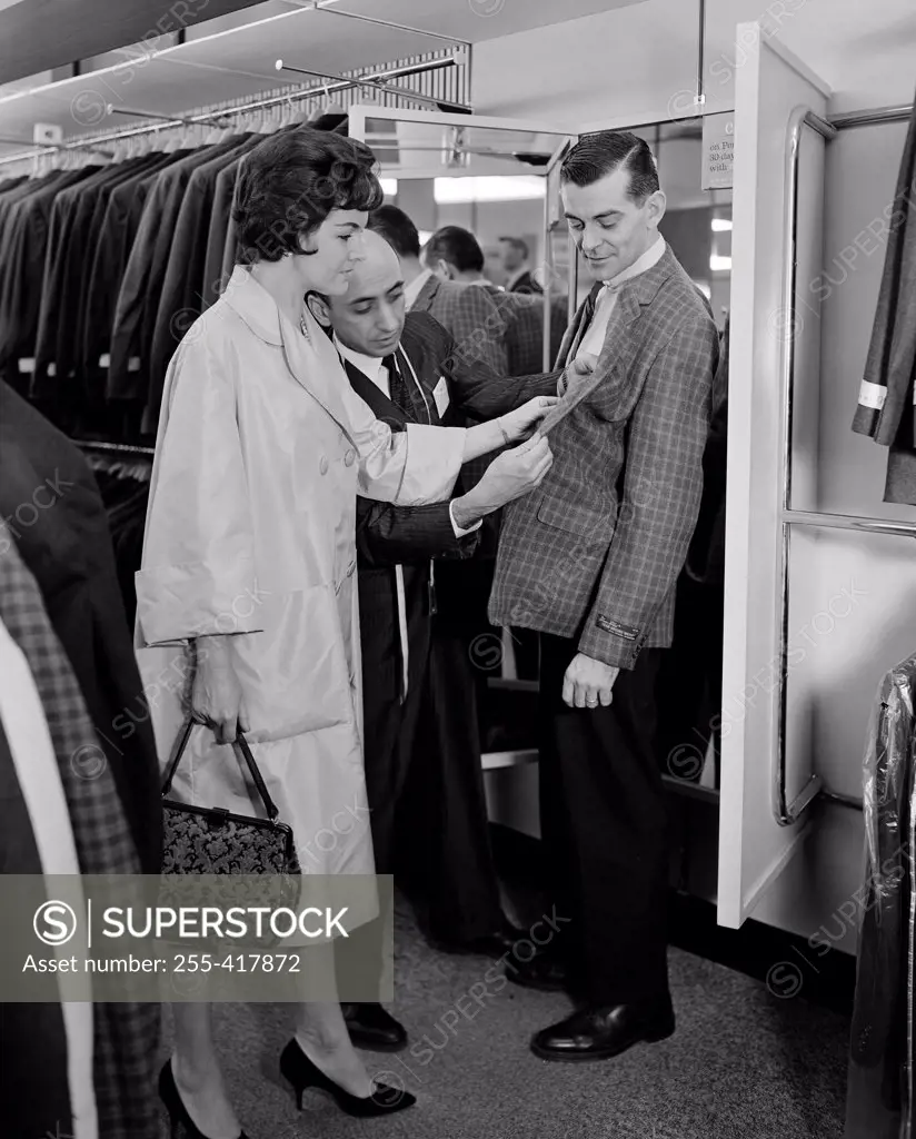 Woman assisting man trying on suit in shop