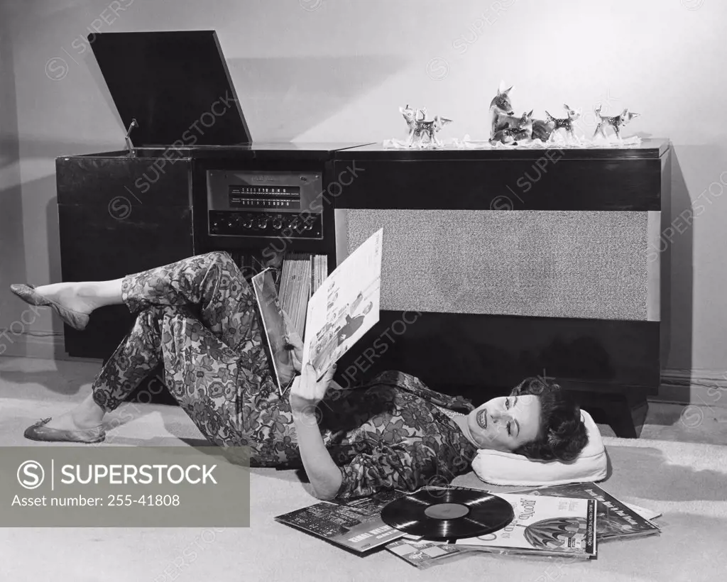 Side profile of a young woman lying on the floor holding records