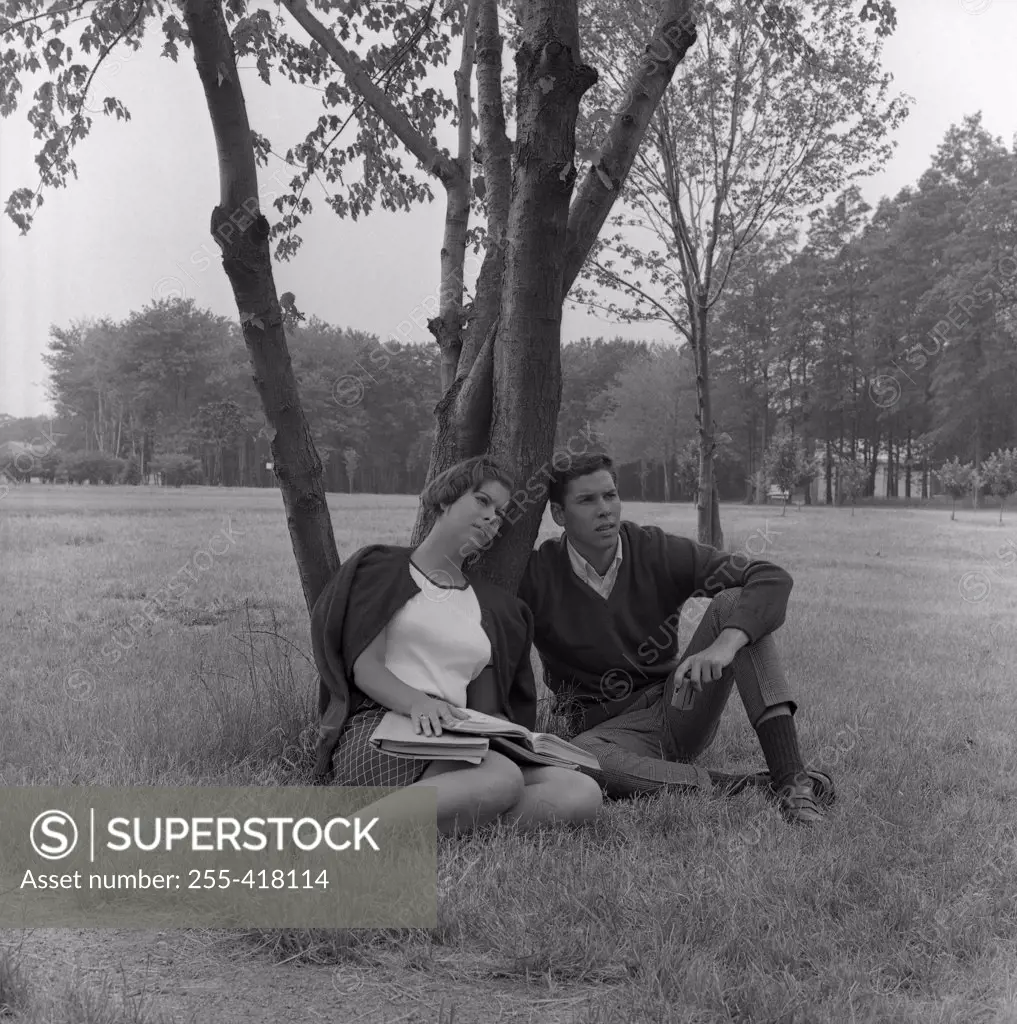 Young couple sitting under tree