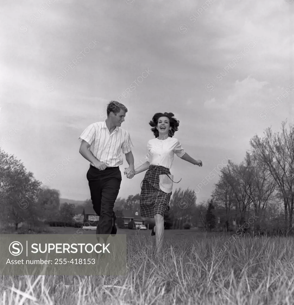 Young couple running through field