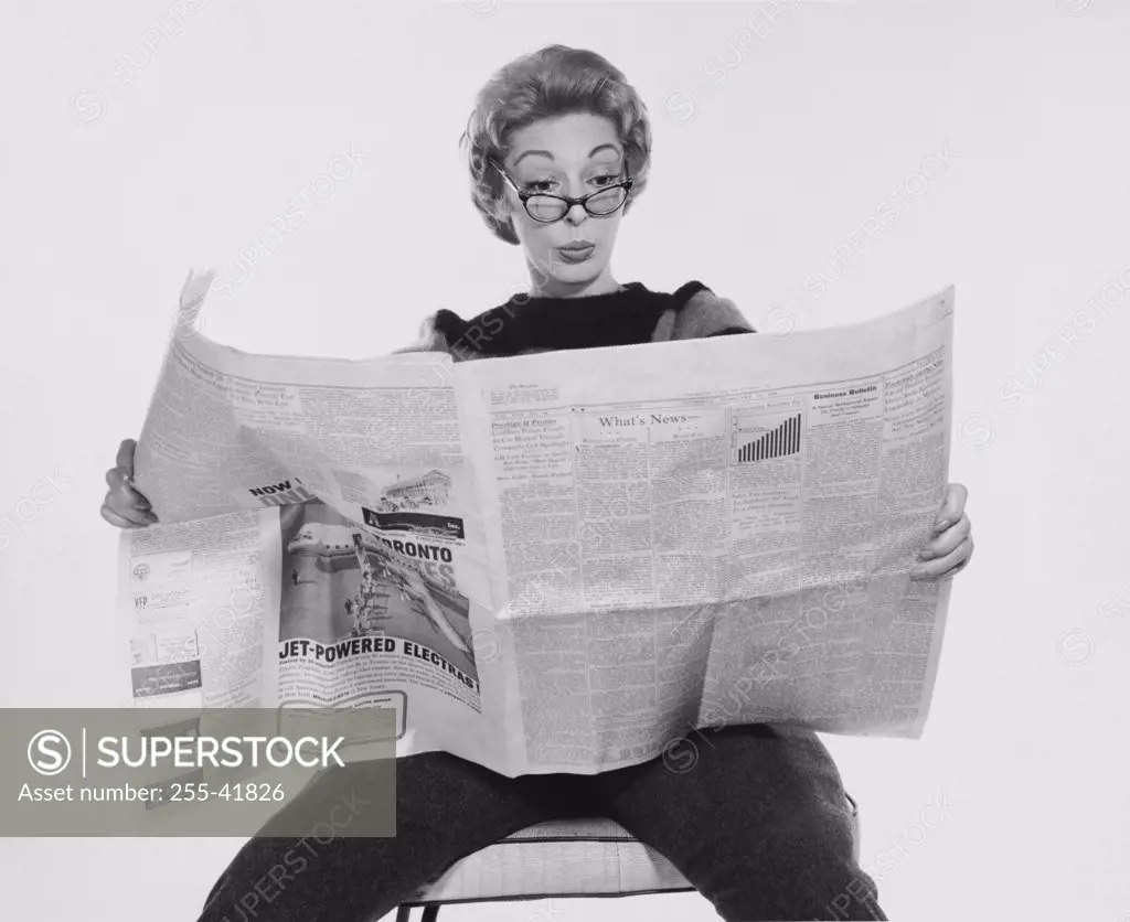 Mid adult woman reading a financial newspaper and making a face
