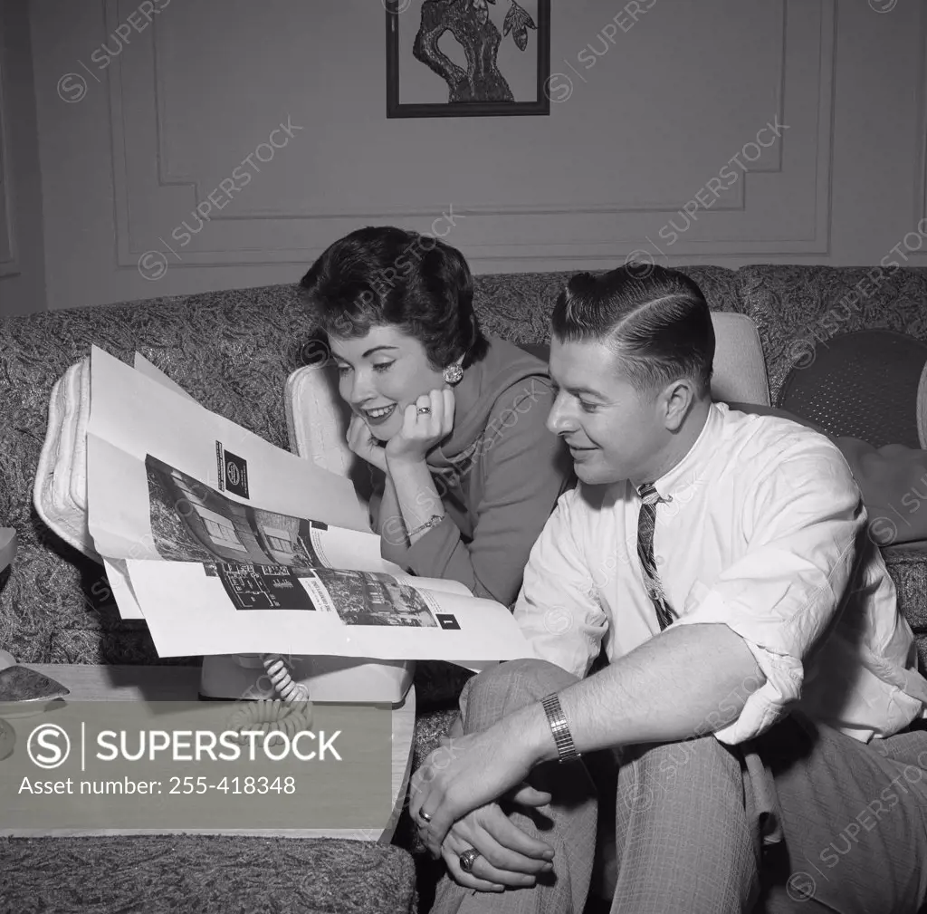 Couple reading adverts in newspaper