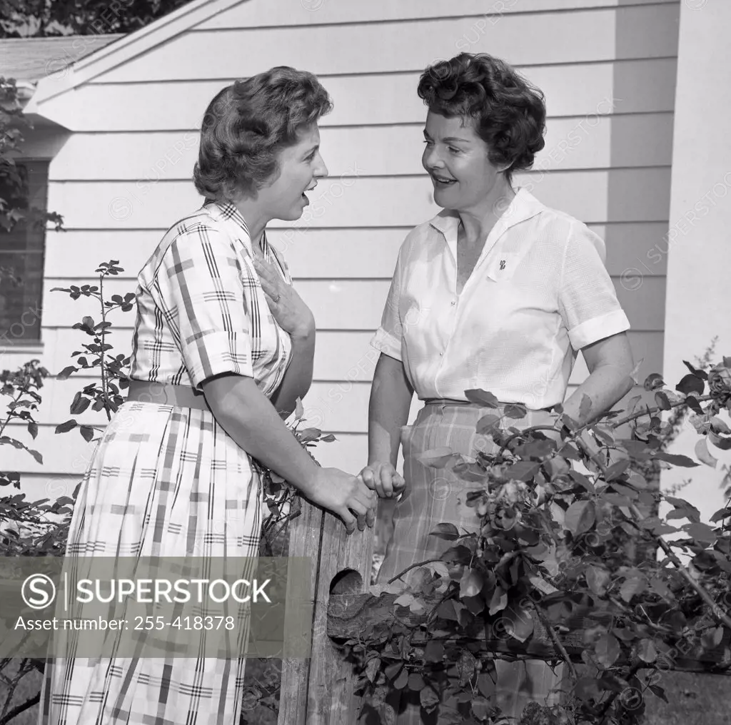 Two women talking over garden fence