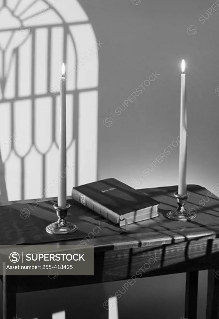 Book on table with burning candles on both sides