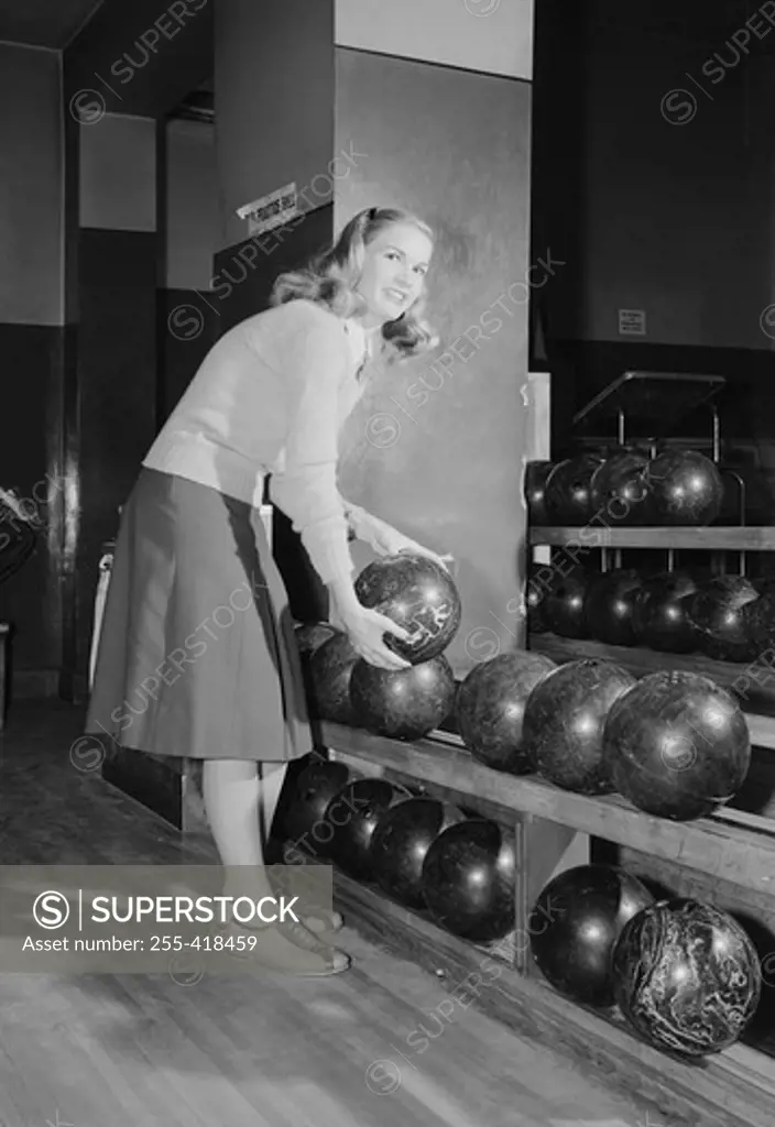 Smiling young woman holding bowling ball