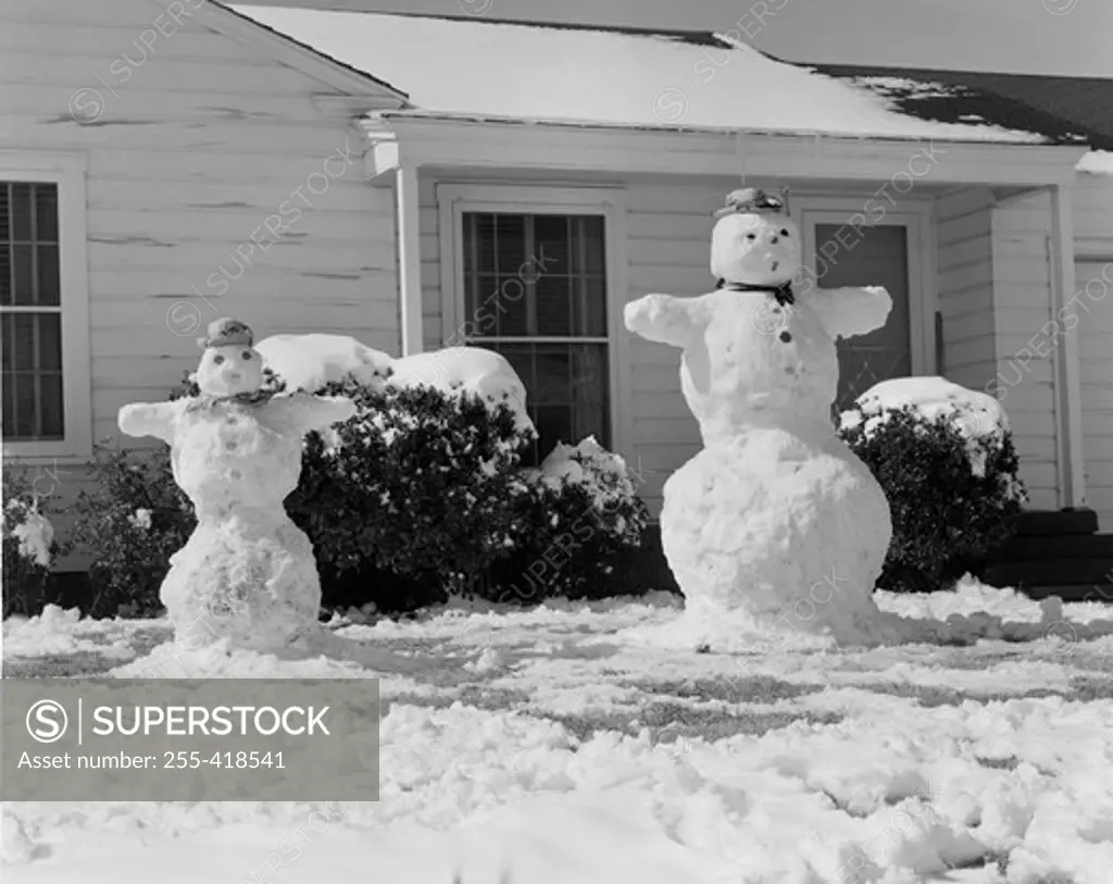 Pair of snowmen in front of home in winter