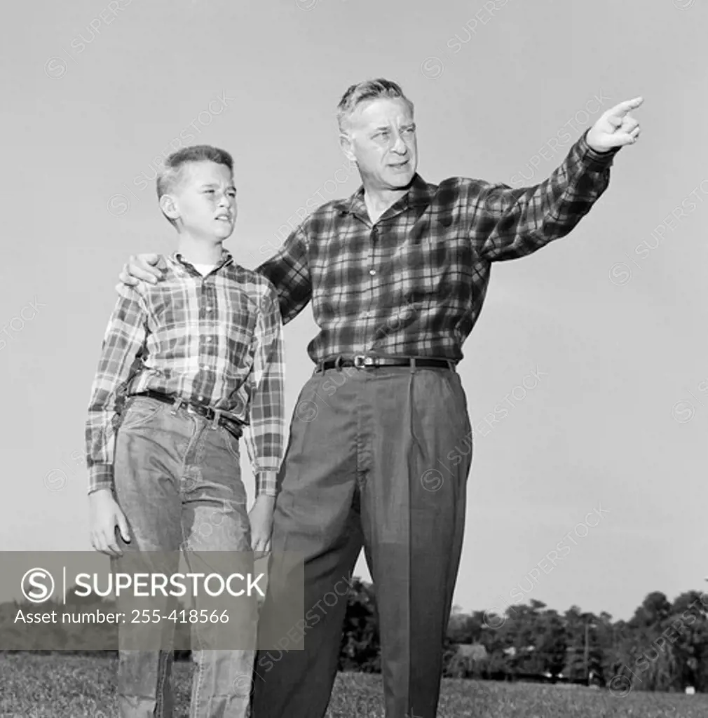 Father and son standing on lawn and looking up