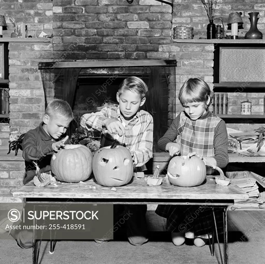 Girl and two boys preparing Jack O' Lantern for Halloween